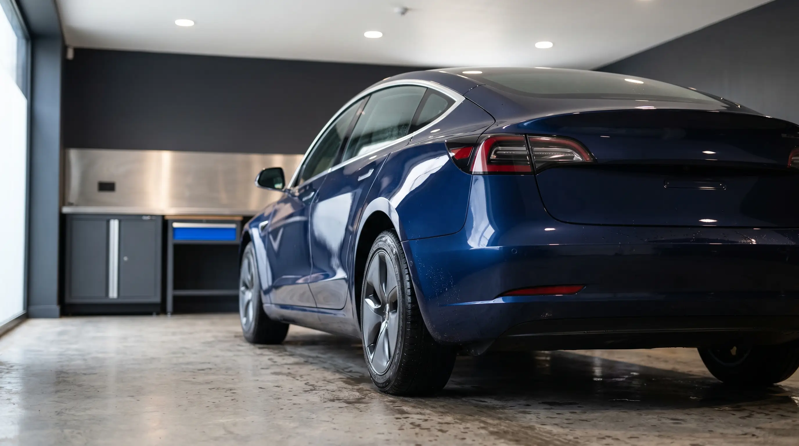An unbranded dark blue car in a tidy garage with directional workshop lighting