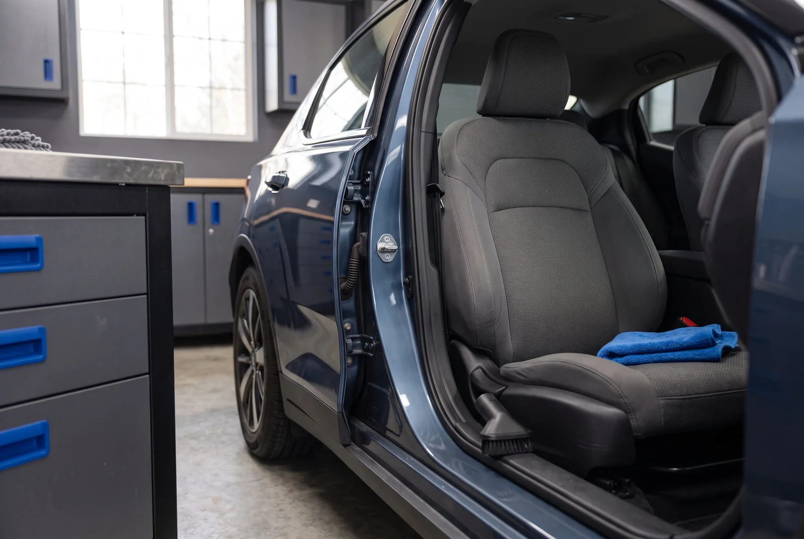 A charcoal fabric car seat with a folded blue microfiber cloth.
