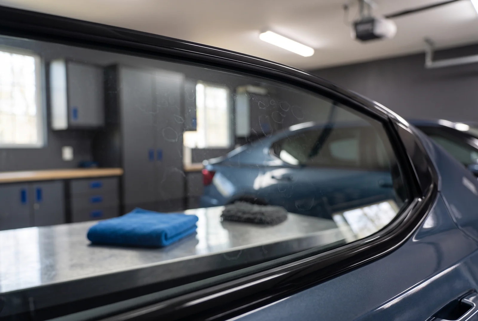 Subtle dried spots on a car side window beside a folded glass cloth.